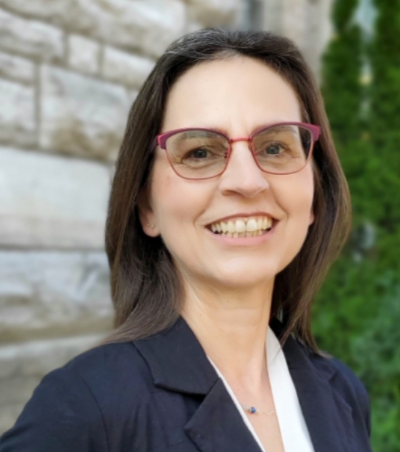 Headshot of Zoe Hilton smiling in front of a stone building.