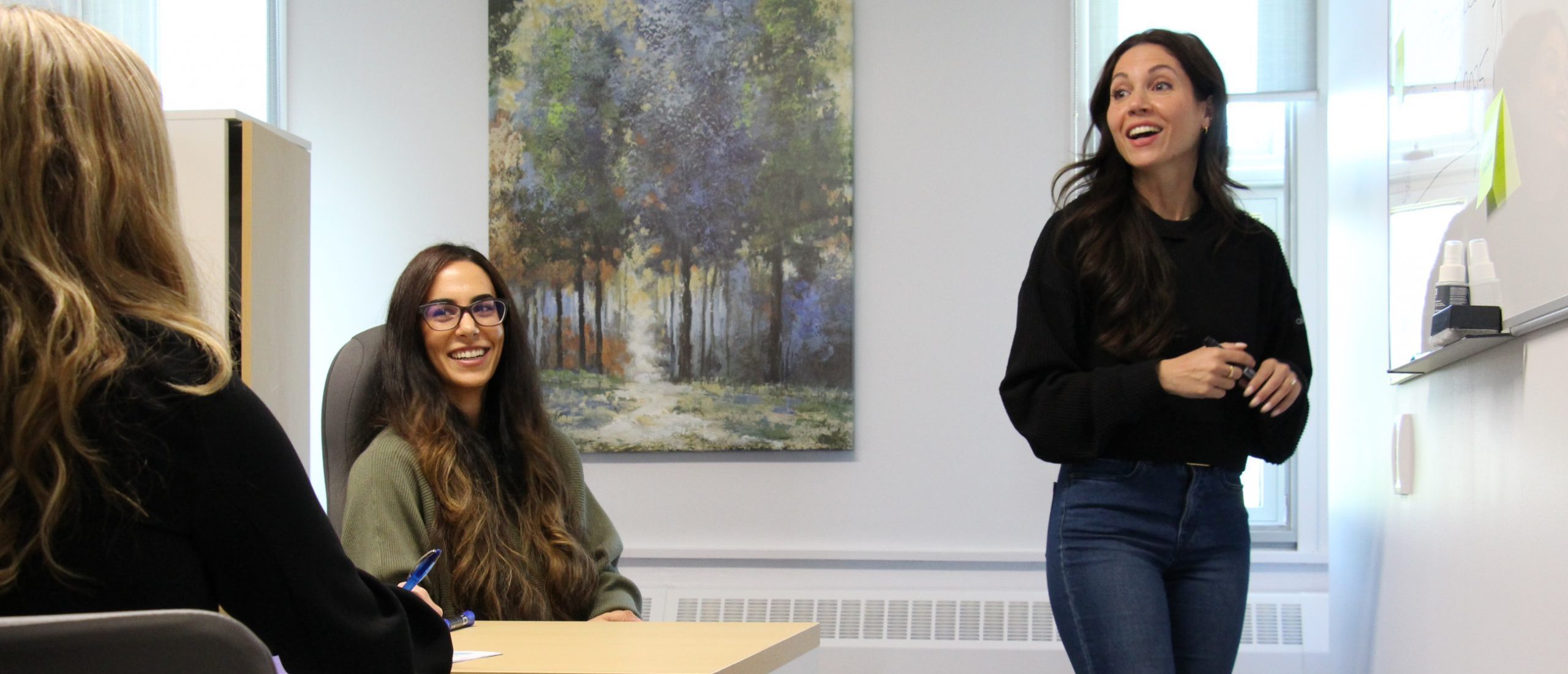 Elnaz Moghimi stands before two women, giving a lively speach.