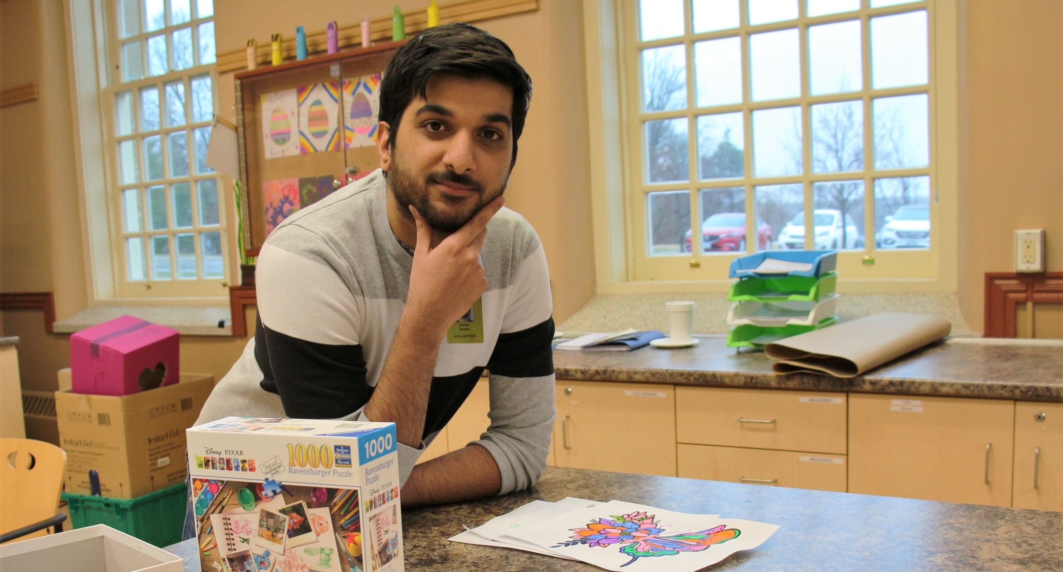 Humza Shahid posing at a table, in front of a partially completed puzzle.