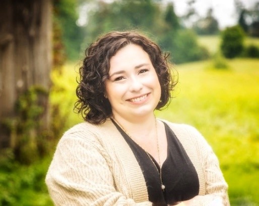 A headshot of Jennifer Schuler smiling with trees surrounding.