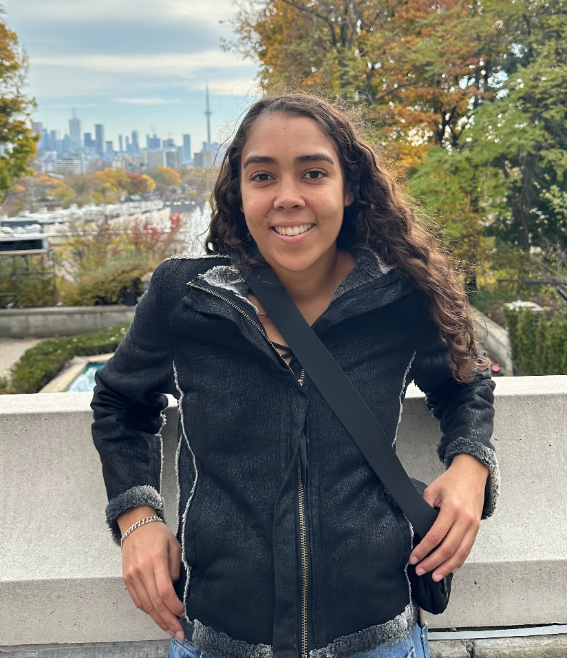 A headshot of Megan Campbell smiling and standing in front of Casa Loma.