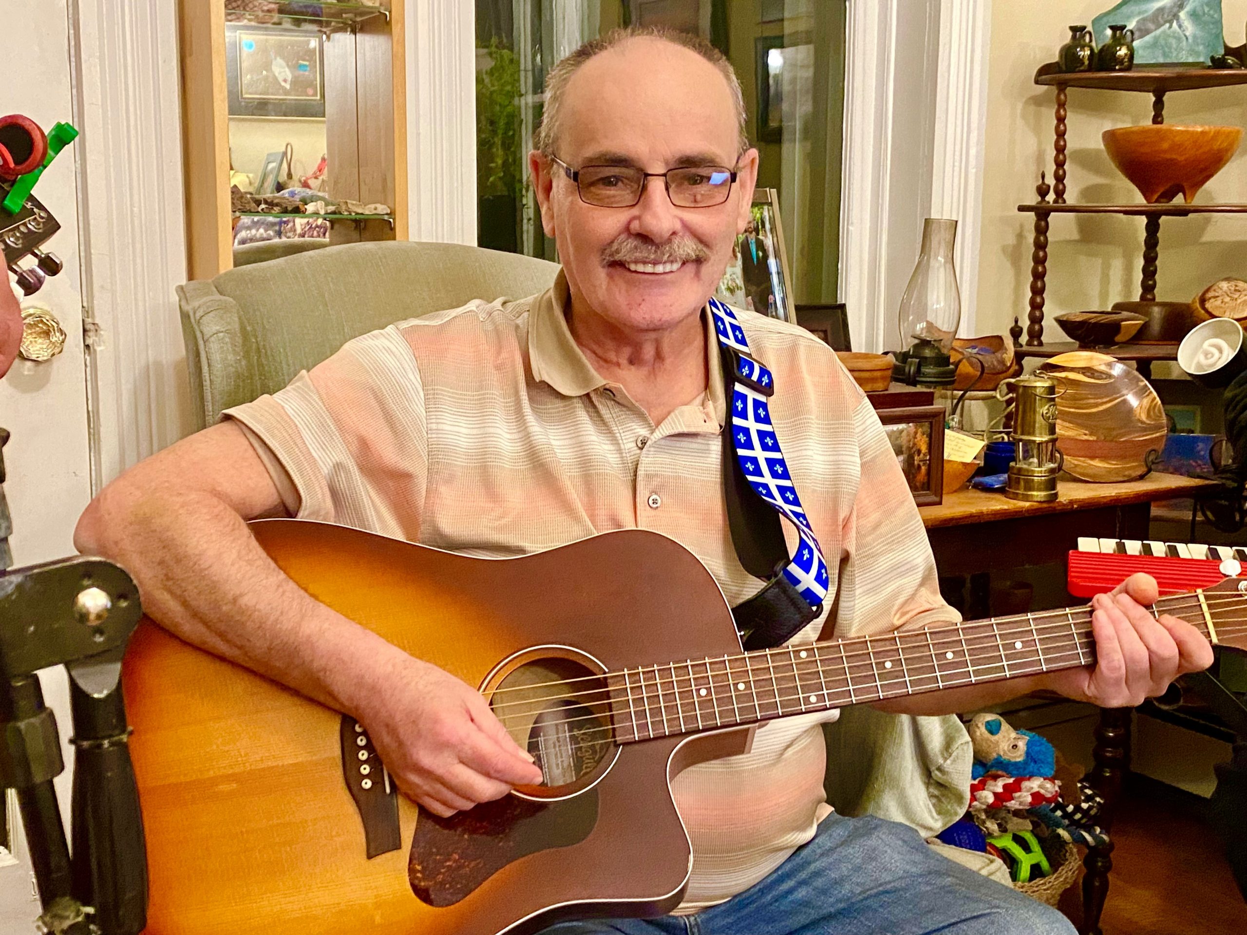 Roger Desroches, playing guitar and smiling broadly.