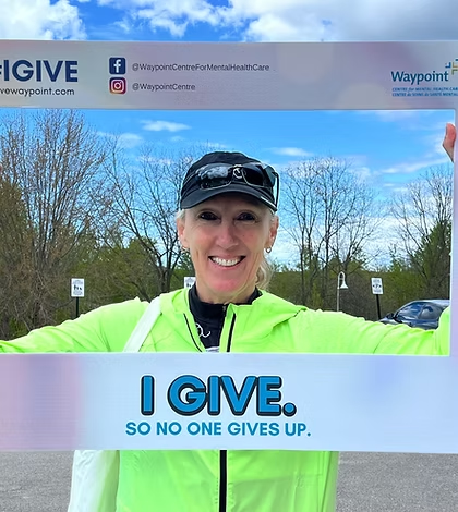 Avery Basset, holding a sign that says "I Give. So no one gives up."